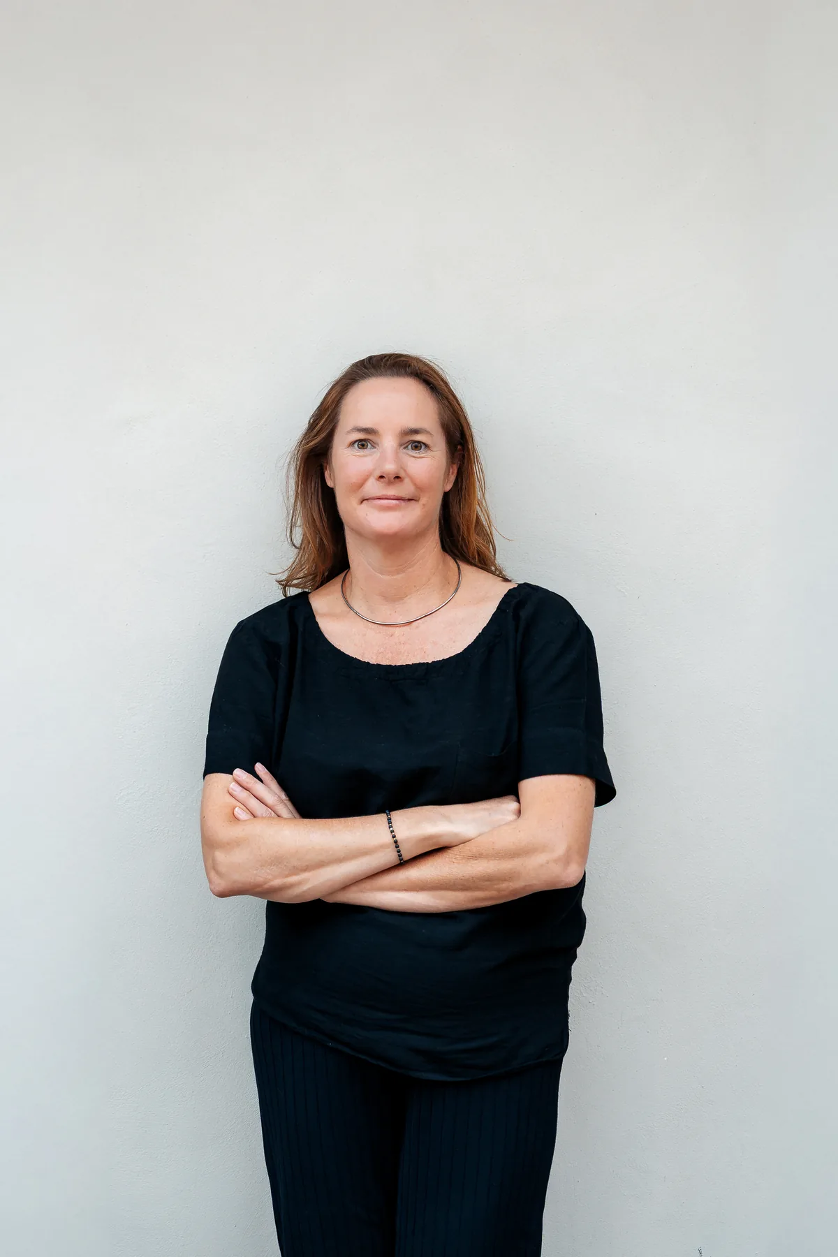Alexia Hoste, met de armen gekruist voor een lichte muur.